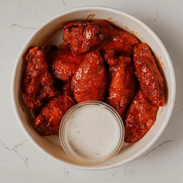 Pazza Pizza's spicy red chicken wings in a white bowl with a side of ranch dressing.