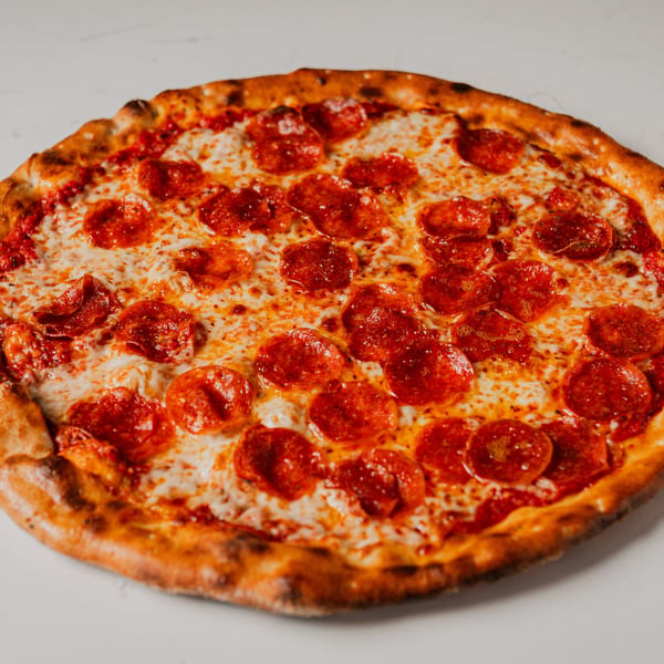 A whole pepperoni pizza from Pazza Pizza, with melted cheese and a golden-brown crust.