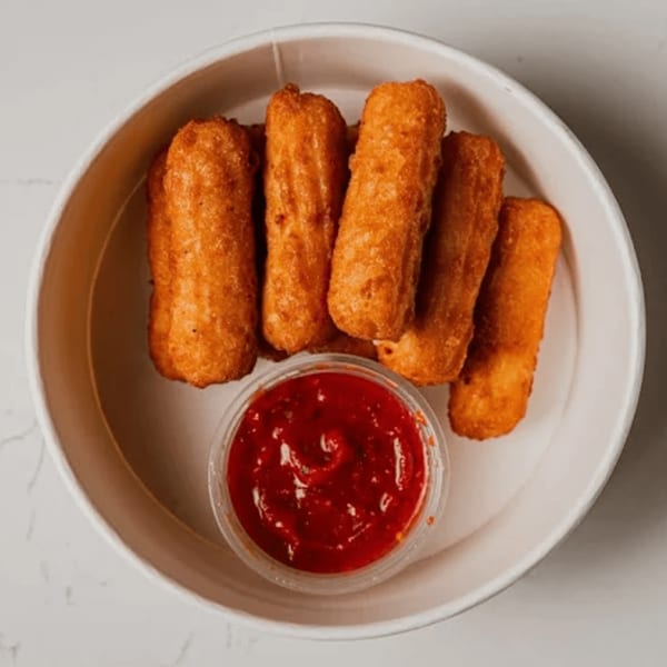 Golden-brown mozzarella sticks and a small container of red marinara sauce in a white bowl.